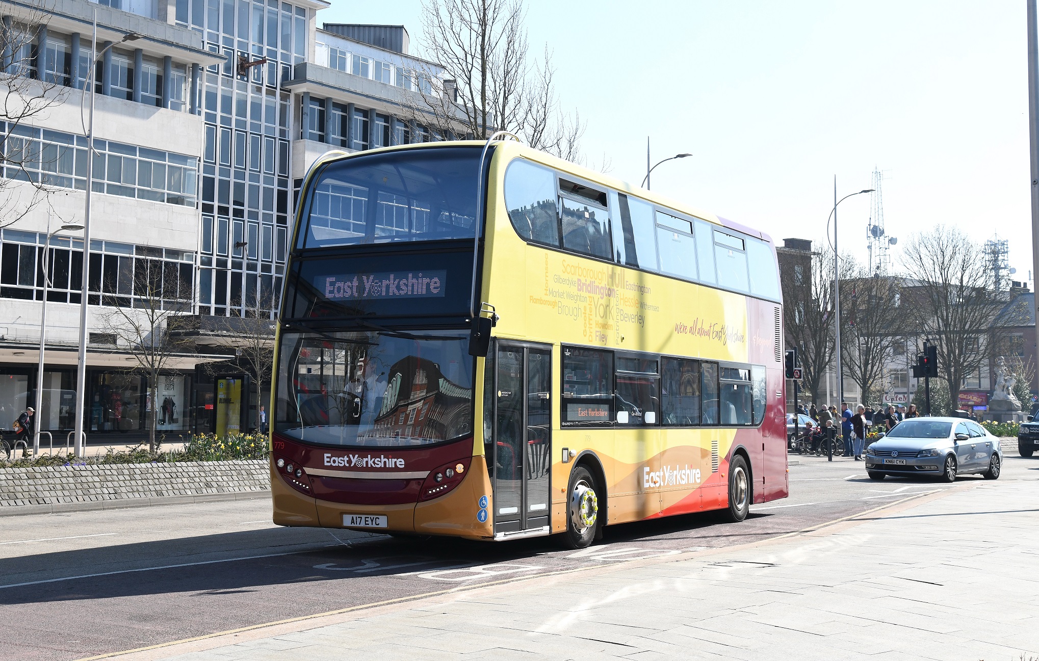 A red and yellow double decker bus driving down a city road.