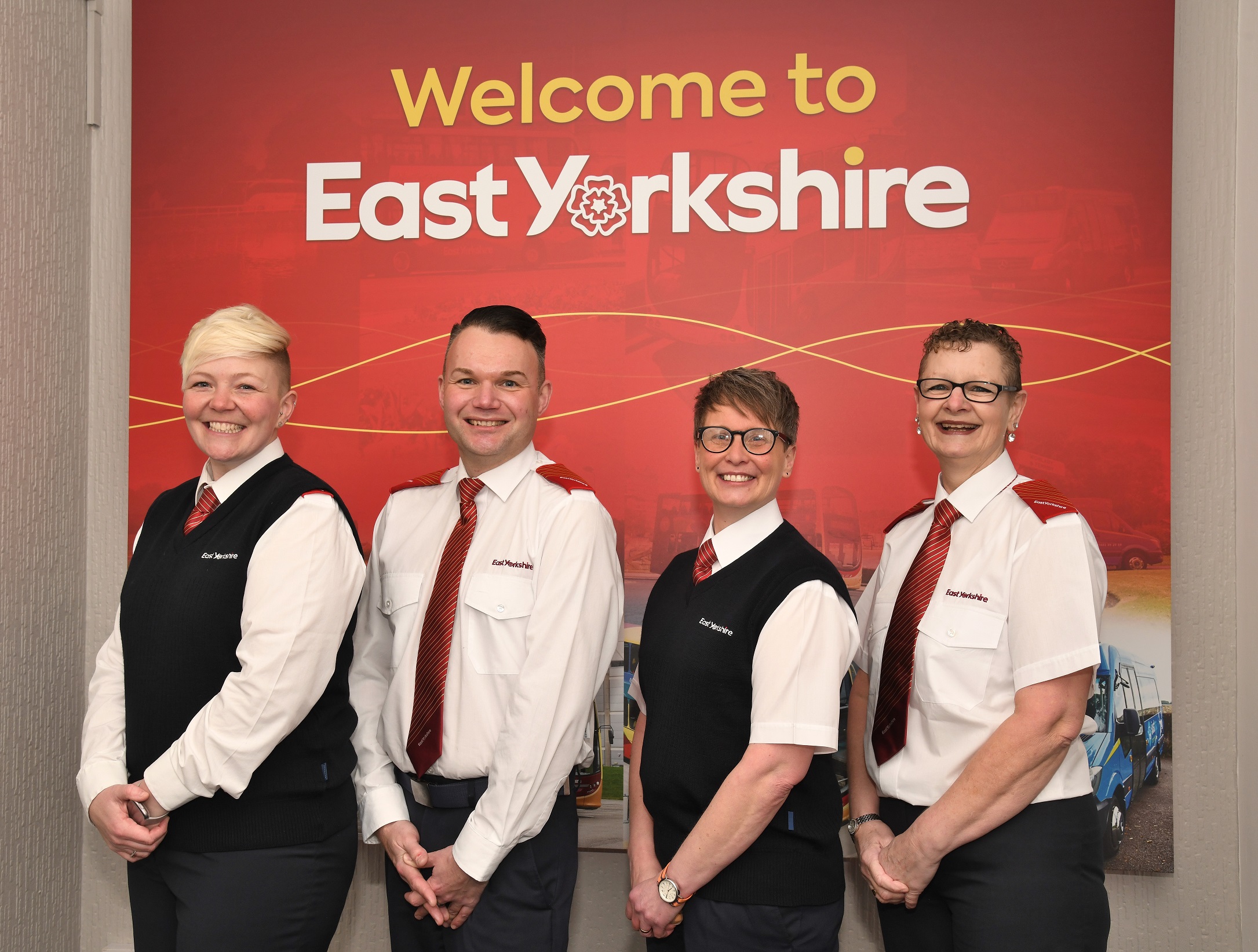 Four East Yorkshire bus drivers stand in front of a sign saying 'Welcome to East Yorkshire'
