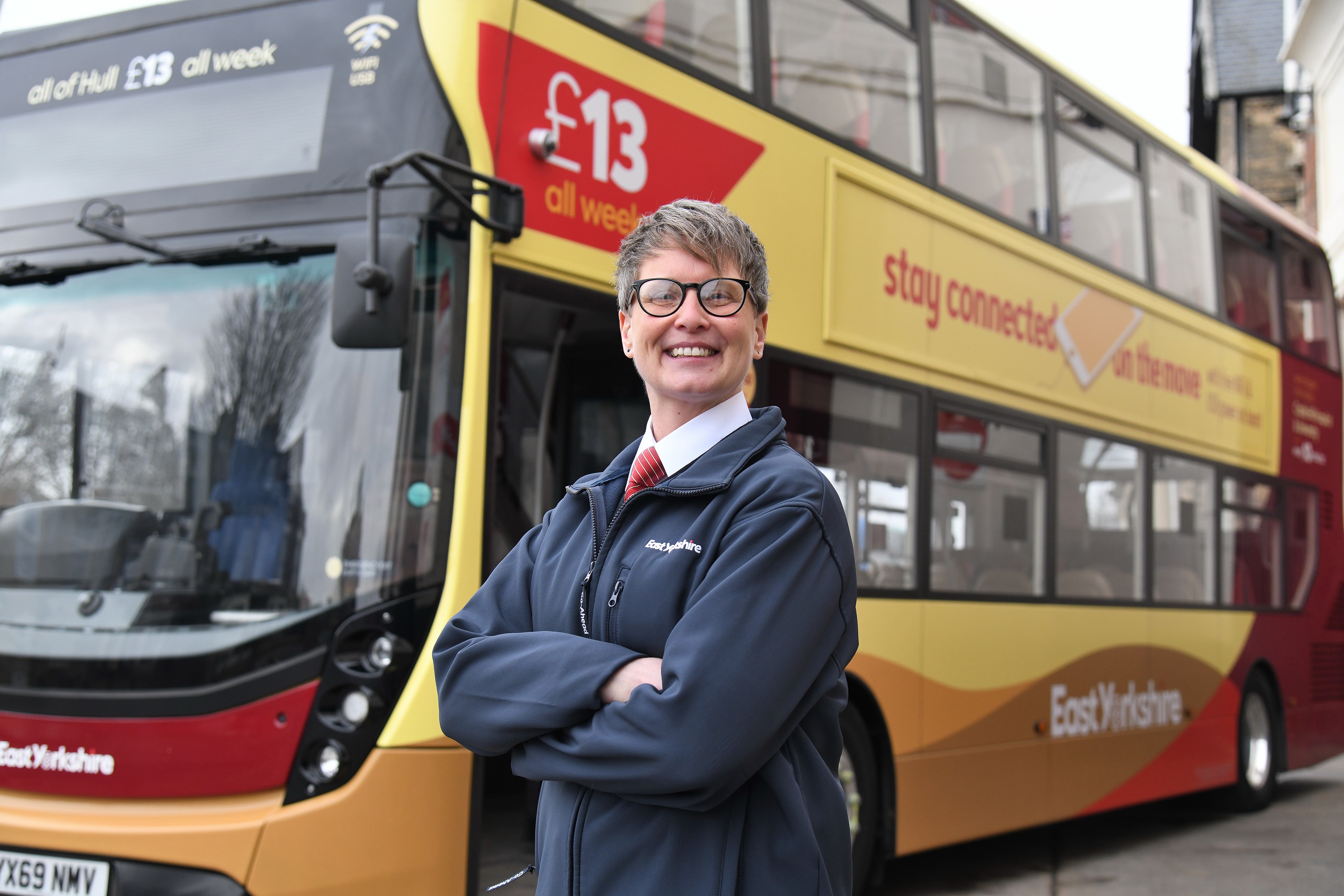 Woman standing in front of red and yellow bus